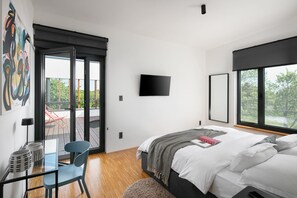 Una camera da letto moderna con un letto grande, una TV montata a parete e un balcone con una sedia.