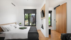 Camera da letto moderna con un letto grande, una TV a parete e una porta scorrevole che conduce al bagno.