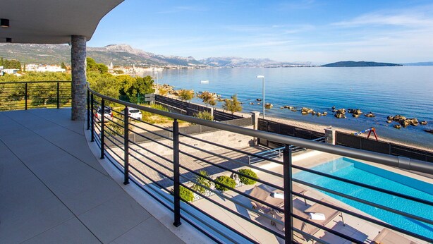 A balcony with a pool, clear blue water, and a view of a coastal town. - Beachfront Villa Atlantis with Pool (Kaštel Štafilić)