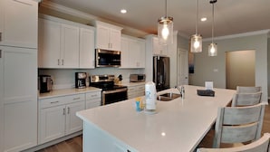 A modern kitchen with white cabinetry, stainless steel appliances, and pendant lighting. - Lost Key Villas #14367 by Southern Vacation Rentals (Pensacola)