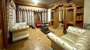 Ein Wohnzimmer mit zwei Ledersofas, einem roten Sessel, einem Holzschrank und einem Kleiderschrank aus Holz.