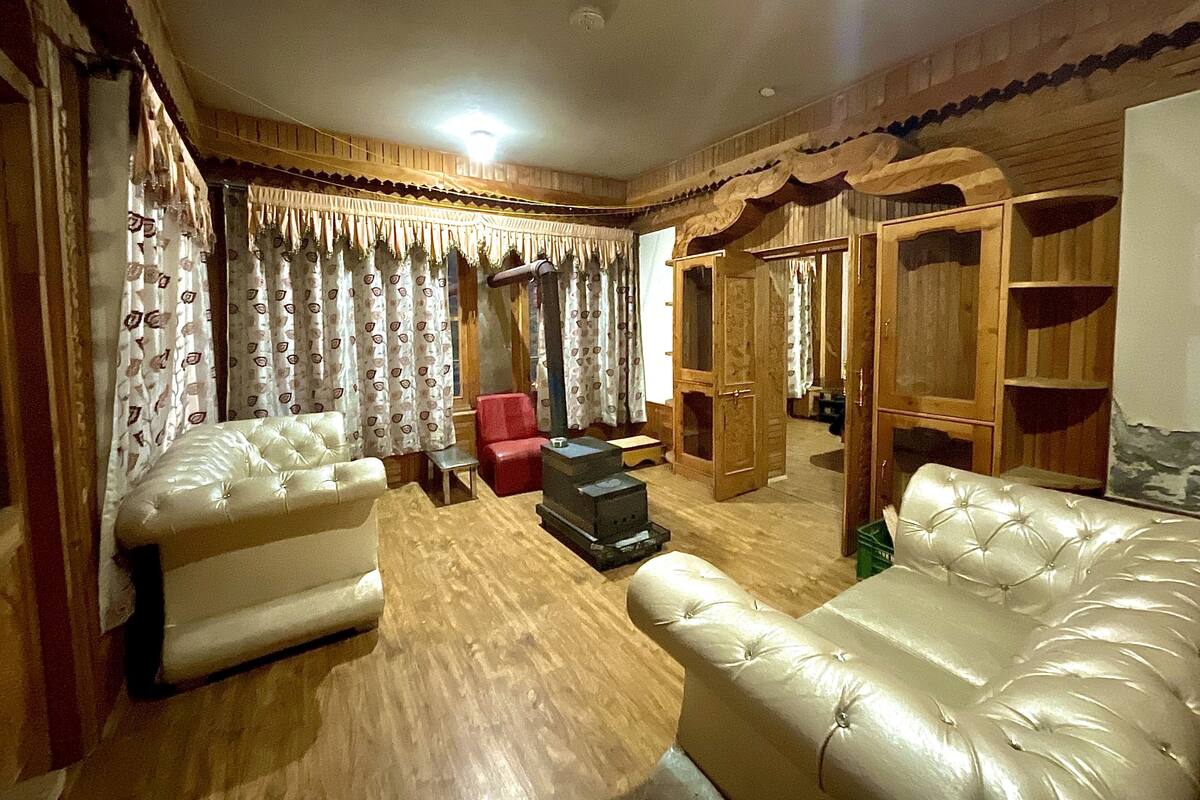 Uma sala de estar com dois sofás de couro, uma poltrona vermelha, um armário de madeira e um guarda-roupa de madeira.