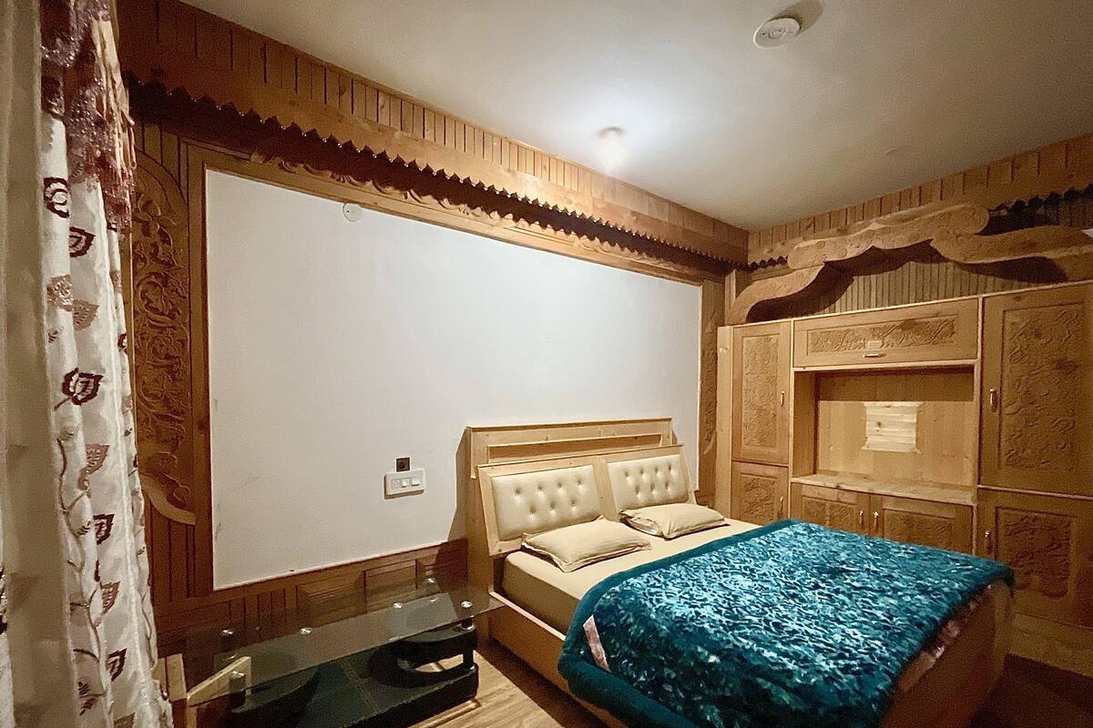 Quarto com cama, guarda-roupa de madeira e espelho.