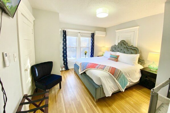 A bedroom with a bed, a chair, a nightstand, a lamp, and a window with curtains. - ELEGANT, SPACIOUS FAMILY HOME - 1/2 MILE FROM WESLEY HOSPITAL - 11 BEDS (Wichita)
