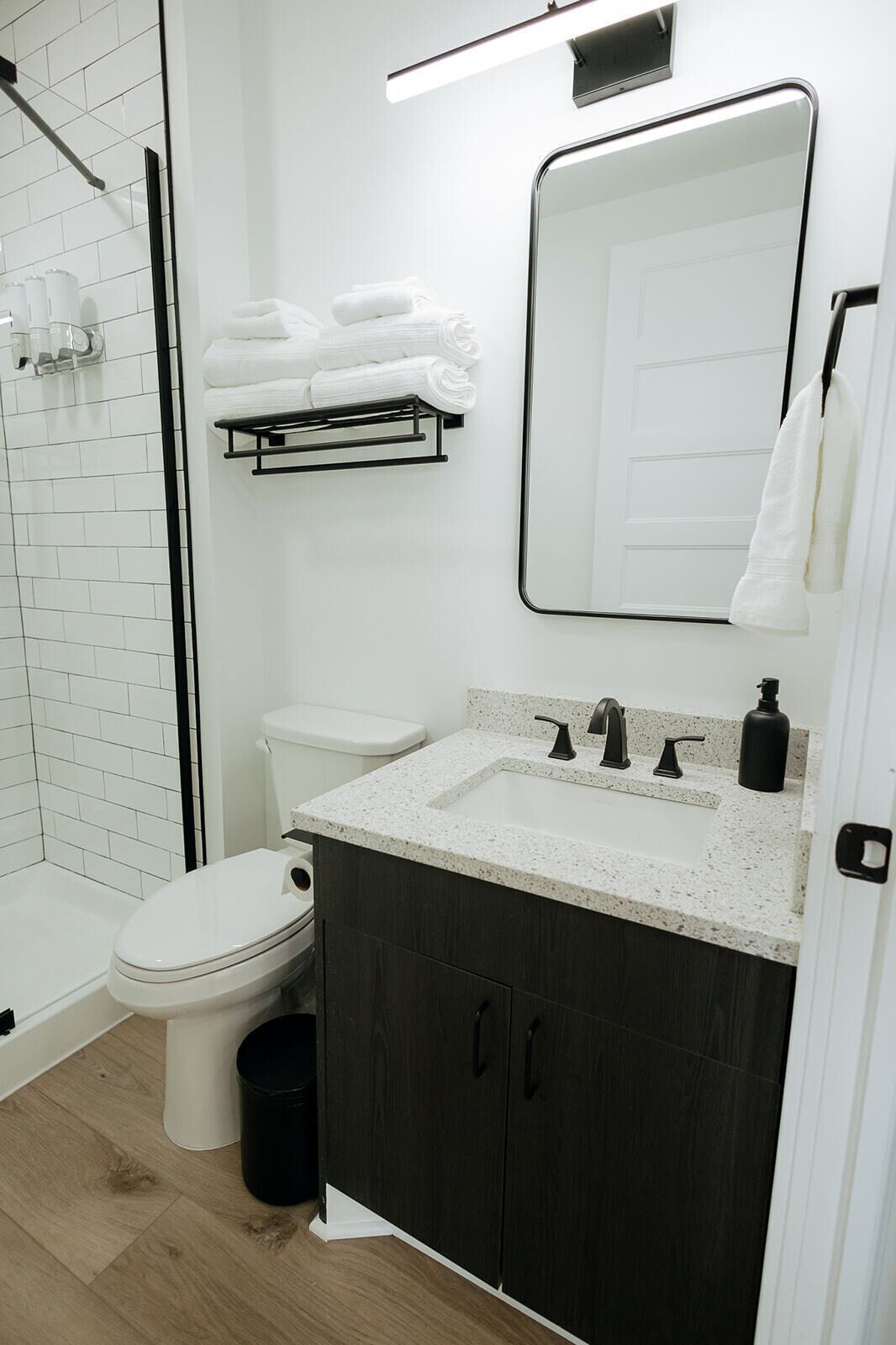 Une salle de bain moderne avec des toilettes blanches, un lavabo doté d’un plan de travail à motifs et un miroir au-dessus du lavabo.