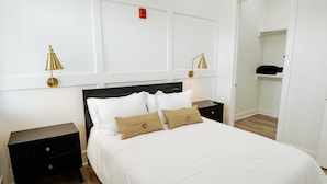 Ein ordentlich eingerichtetes Schlafzimmer mit einem großen Bett, zwei Nachttischen und zwei Wandleuchten.