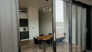 Ein modernes Interieur mit Essbereich, Küche und einer Glastür zum Balkon.