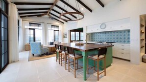 A spacious kitchen with a central island, large windows, and a dining area with a sofa and chairs. - Las Catalinas- Spectacular views- breakfast service, Casa Chameleon's neighbor (Las Catalinas)