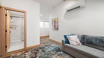 Un salon moderne avec un canapé gris, un tapis coloré et un tableau accroché au mur.