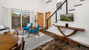 Ein modernes Wohnzimmer mit Essbereich, einer Treppe und einem an der Wand befestigten Fernseher.