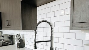 Una cocina con un lavamanos doble, armarios de madera y salpicadero de azulejos blancos.