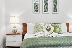 A hotel room with a bed, a nightstand with a lamp, and three framed wall art pieces. - Splash 804E (Panama City Beach)