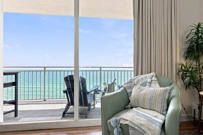 A balcony with a view of the sea, a green sofa with a patterned throw, and a potted plant. - Splash 804E (Panama City Beach)