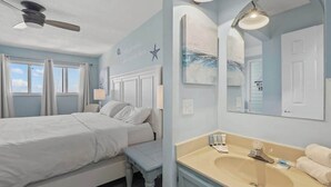 Un dormitorio con cama, mesita de noche y ventilador de techo.