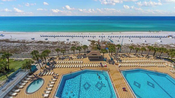 Un resort con varias piscinas, playa y vista al océano.