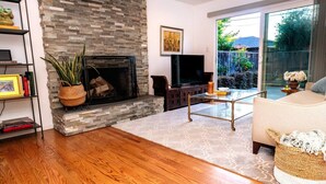 Una sala de estar con chimenea de piedra, televisor y sofá.