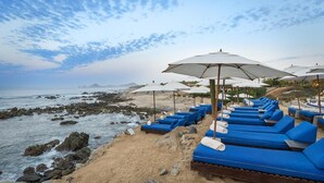 A beachside lounge area with blue lounge chairs and white umbrellas, overlooking the ocean and rocky shoreline. - Christmas or NYE in CABO!
Private Pool with Ocean View!
Entire Villa all for YOU (Cabo San Lucas)