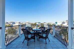 A balcony with a table and four chairs, overlooking a residential area. - Blu Flamingo-Free Golf Cart-Pool Heat Deals (Destin)