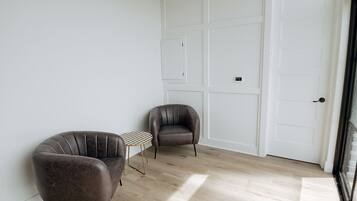 Une pièce avec deux fauteuils en cuir, une petite table ronde et une porte blanche.