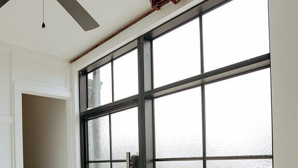 A room with a large sliding glass door leading to a balcony, a ceiling fan, and a wooden floor. - Walk To Intrust Arena - Modern Boxcar experience! (Wichita)