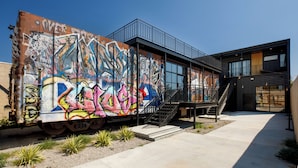 A modern building with a large graffiti-covered train car attached to its side. - Walk To Intrust Arena - Modern Boxcar experience! (Wichita)