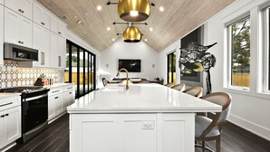 Una cocina moderna con armarios blancos, una isla central y un ventanal amplio.
