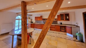 Una cocina amplia con vigas de madera, encimeras de granito y piso de baldosas.
