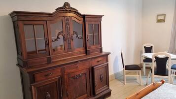 Ein Zimmer mit einem großen Holzschrank, einem Esstisch mit Stühlen und einem Bett.