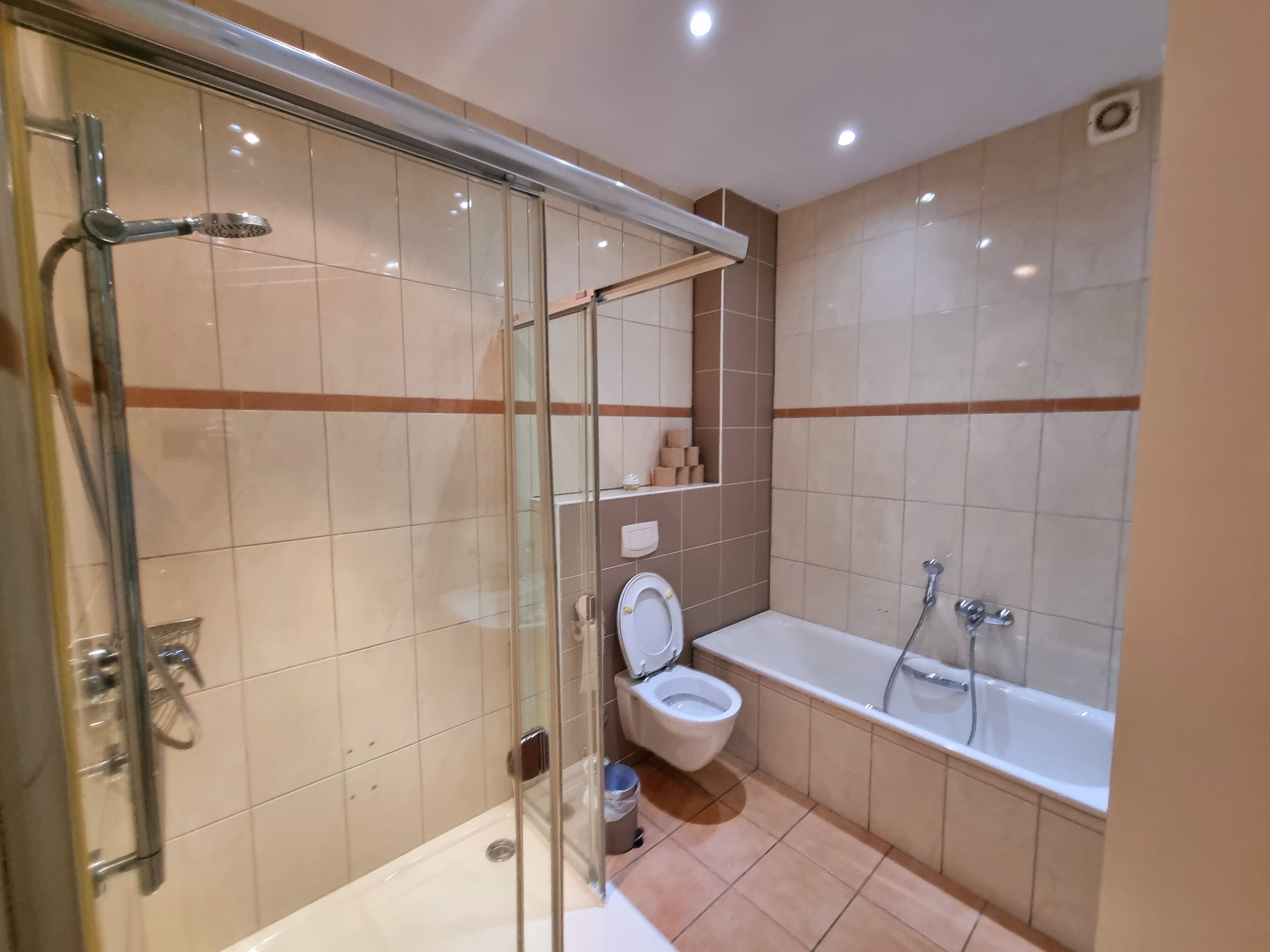 A modern bathroom with a glass-enclosed shower, a toilet, and a bathtub.