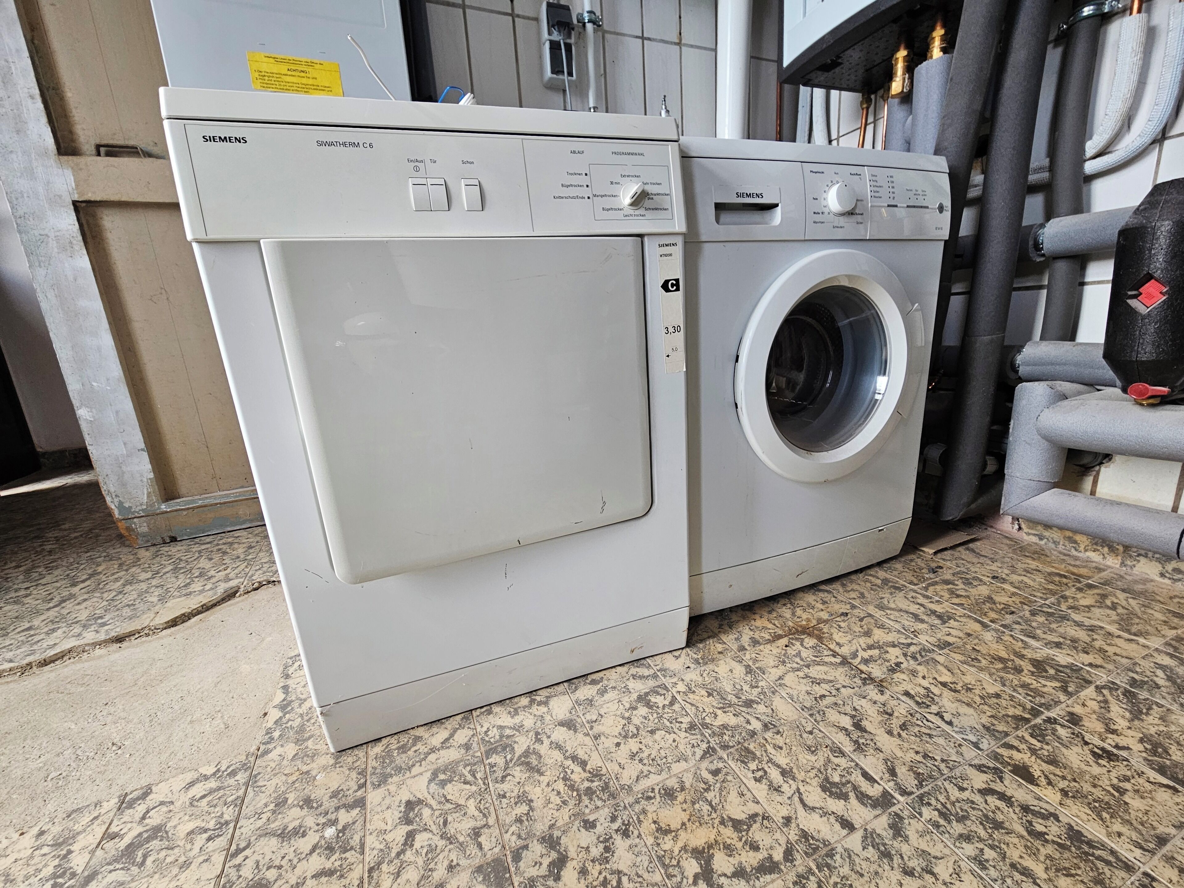 A white Siemens SWATHERM C6 washing machine with a control panel, a front door, and a water inlet hose.