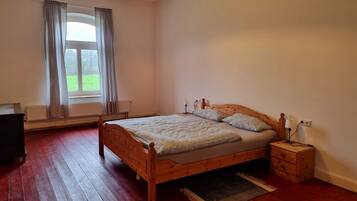 Un dormitorio con una cama de madera, una mesita de noche, una lámpara y una ventana con cortinas.