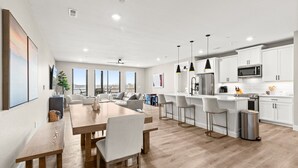 Una cucina moderna con mobili bianchi, elettrodomestici in acciaio inossidabile e un tavolo da pranzo in legno.