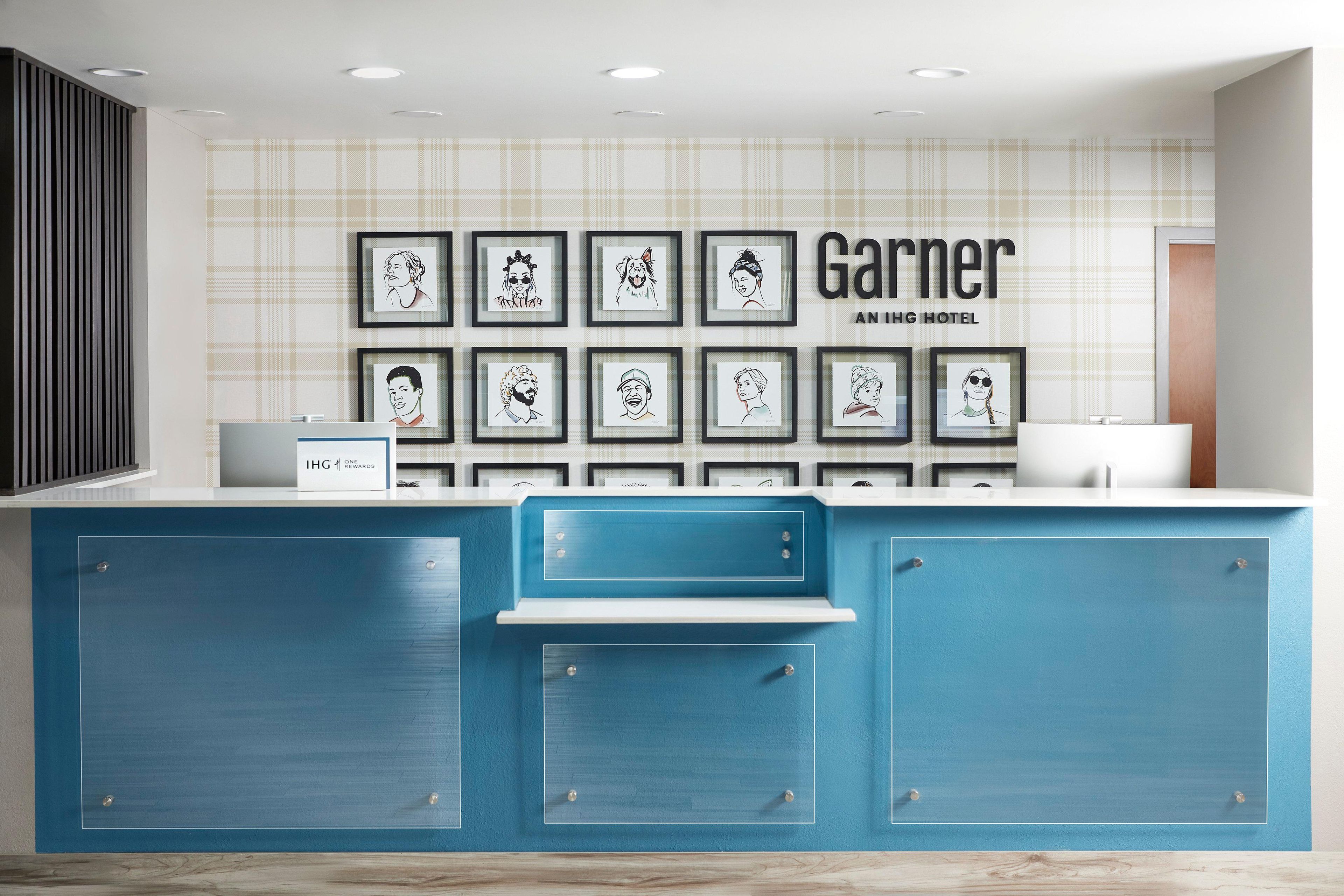 Un comptoir d’accueil d’hôtel avec des œuvres d’art encadrées accrochées au mur et une enseigne indiquant « Garner An High Hotel ».