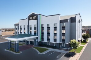 A modern hotel with a prominent sign, a covered entrance, and a parking lot.