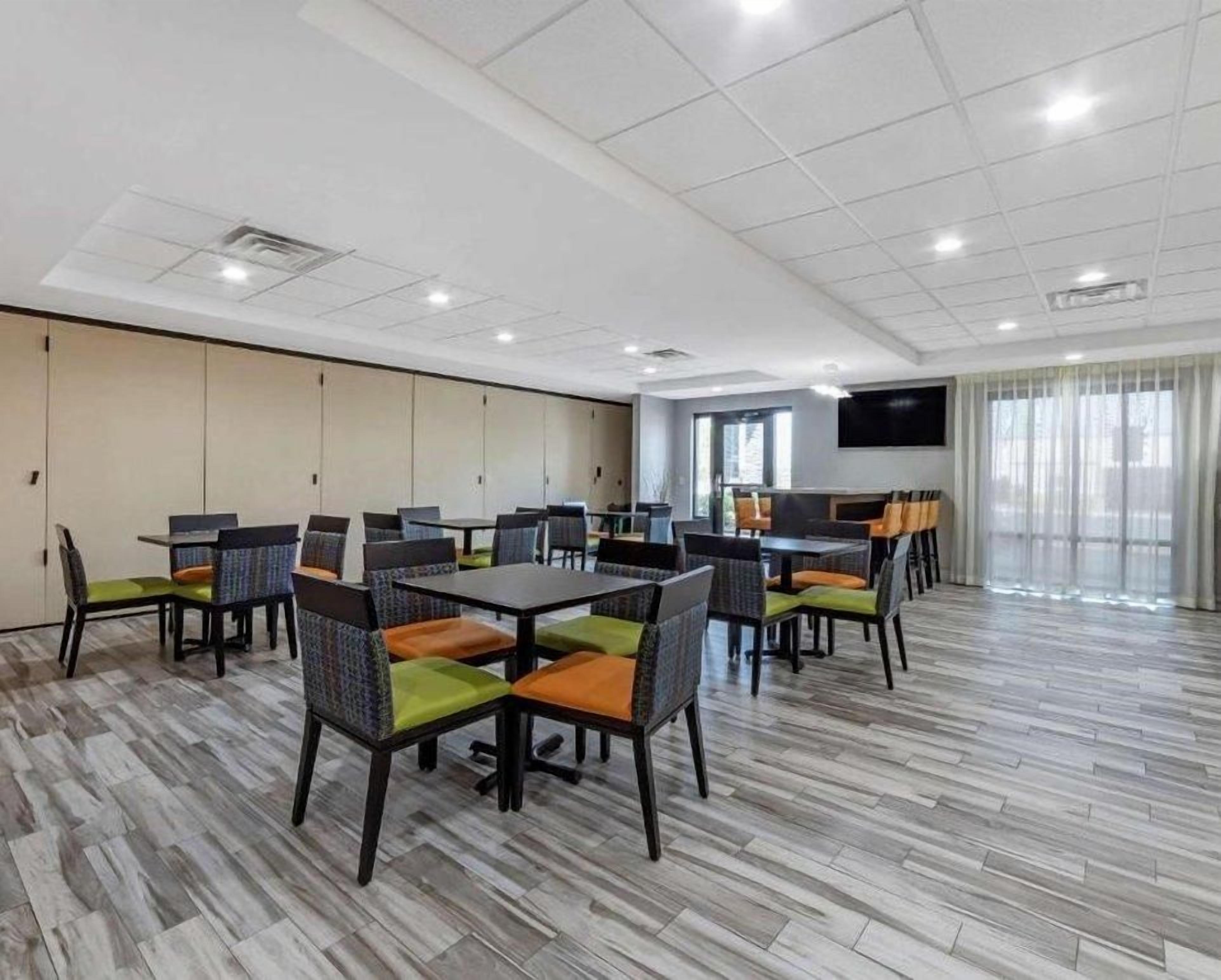 A conference room with tables and chairs, a flat-screen TV, and a large window.