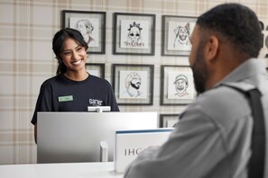 Un espace d’accueil avec un comptoir d’enregistrement, des œuvres d’art encadrées accrochées au mur et un badge nominatif posé sur le comptoir.
