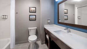 A modern bathroom with a white toilet, a large mirror, and a white sink.