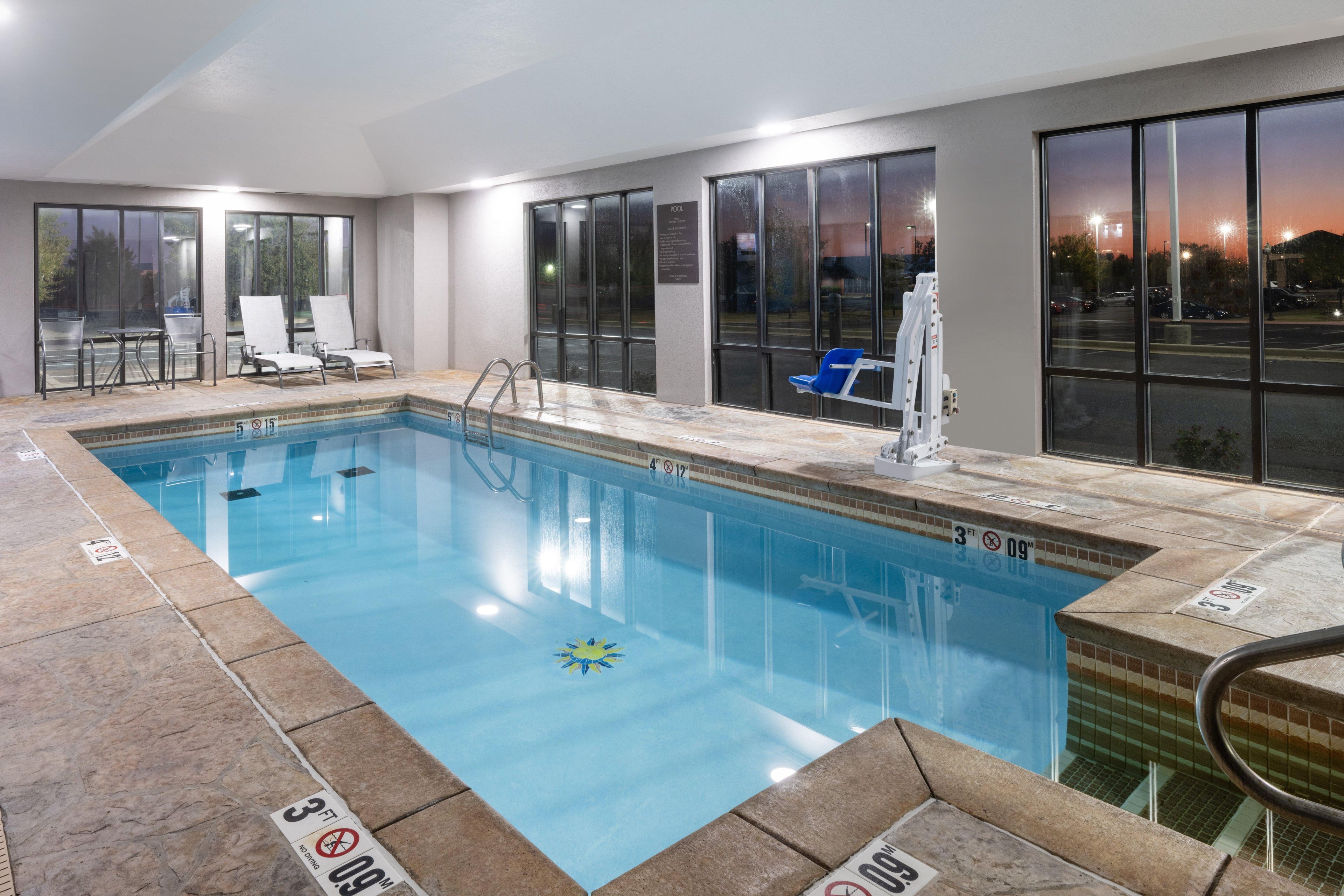 A swimming pool with clear water, a diving board, and lounge chairs.