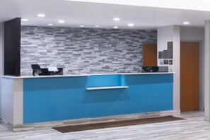 Una recepción con un muro azul decorativo, suelo de madera y diseño moderno.