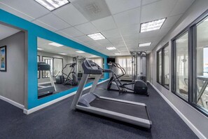 A gym with treadmills, exercise bikes, and a mirrored wall.