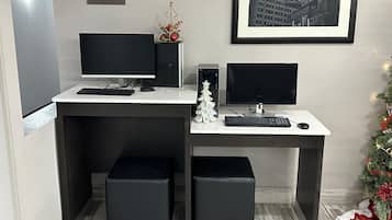 A workspace with two monitors, a keyboard, a mouse, and a small Christmas tree.