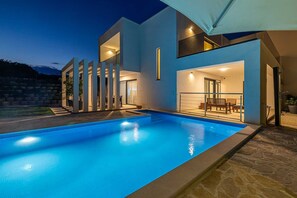 A modern house with a swimming pool, outdoor seating, and a large umbrella. - Villa SPLENDIDA with private pool (Žgaljići)