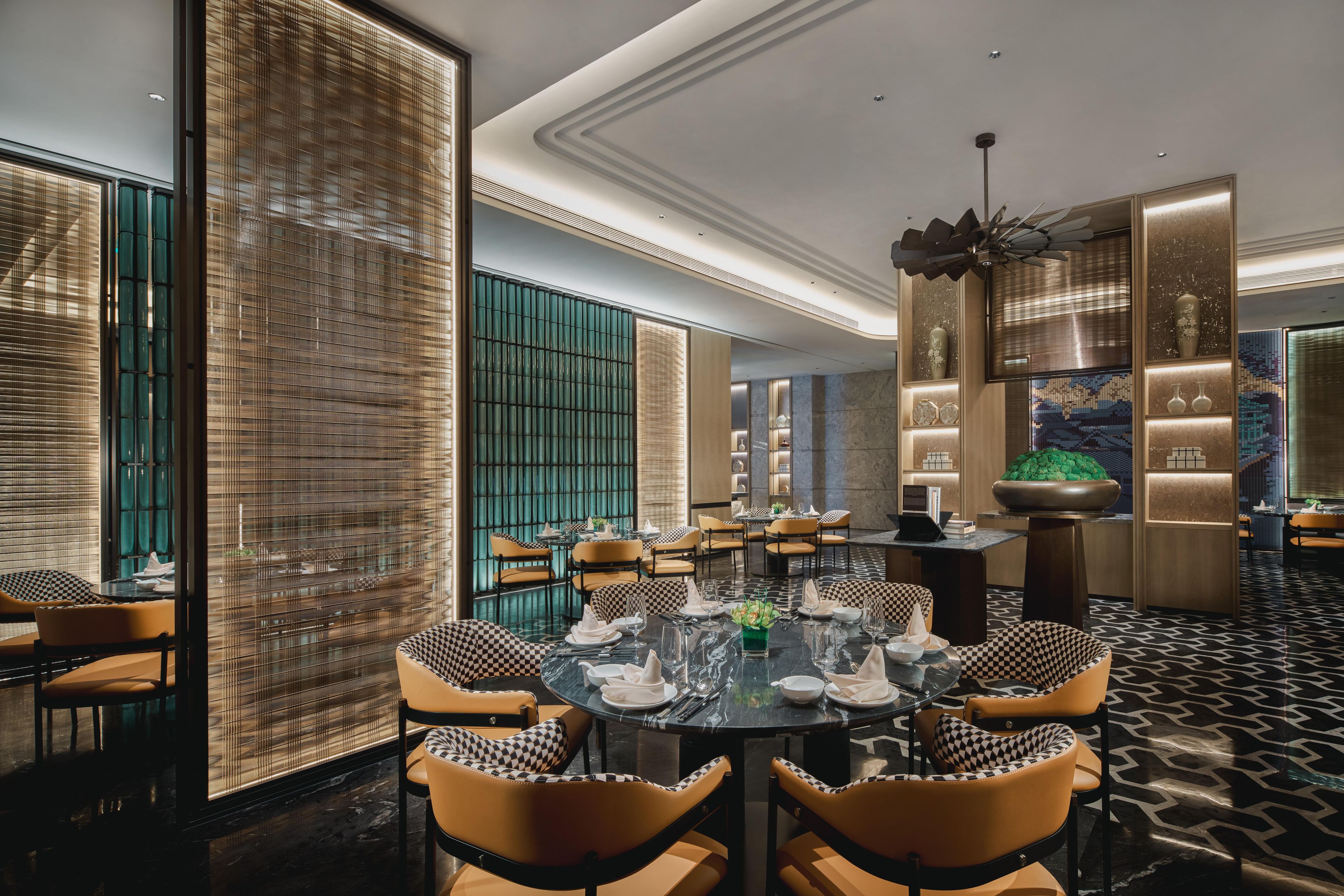 A modern dining area with round tables, checkered chairs, and a decorative ceiling fan.