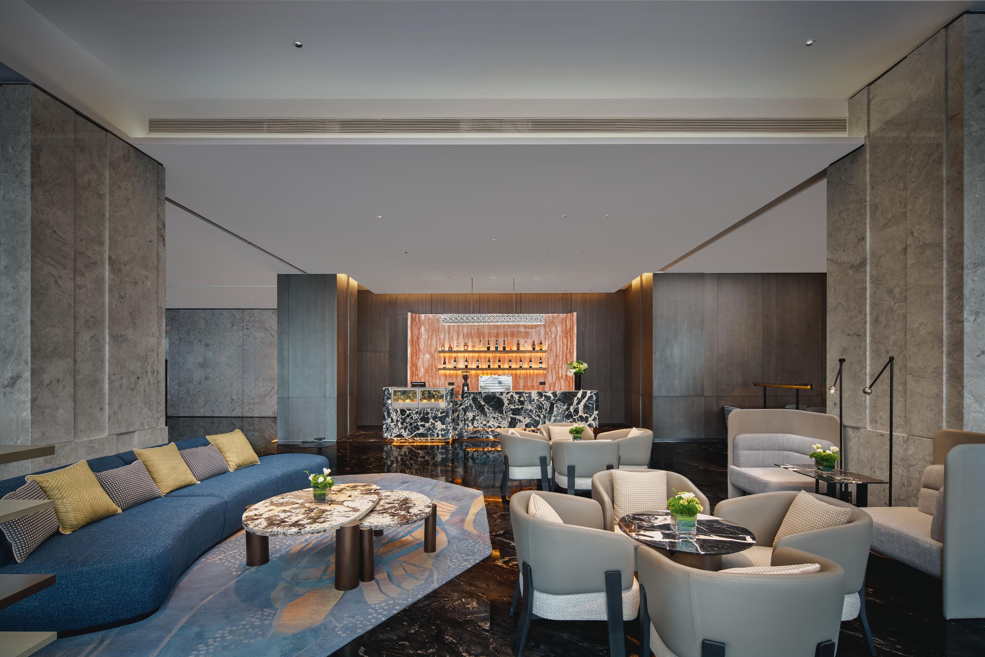 A modern lounge area with a blue sofa, round coffee table, and seating arrangements.