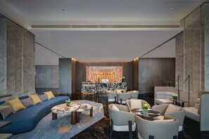 A modern lounge area with a blue sofa, round coffee table, and seating arrangements. - Crowne Plaza Shangluo (Shanglou)