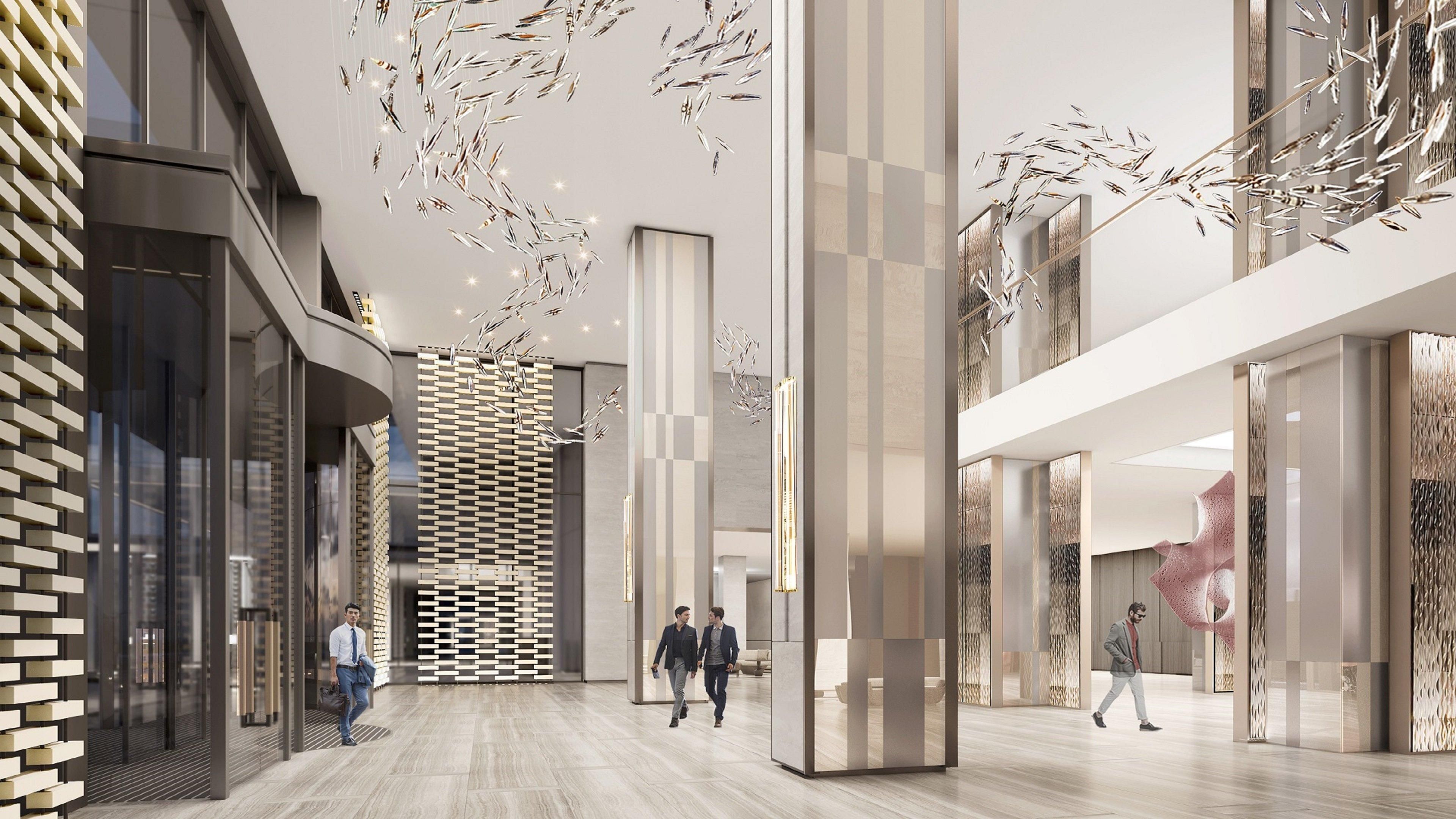 A spacious, modern lobby with a high ceiling, geometric wall patterns, and a central walkway.
