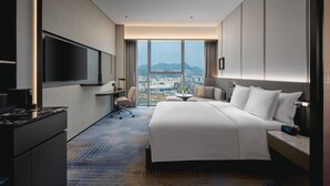 A modern hotel room with a large bed, a desk, a flat-screen TV, and a city view. - Crowne Plaza Shangluo (Shanglou)