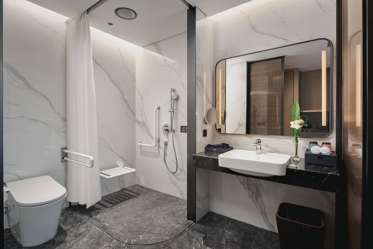 A modern bathroom with a toilet, shower, and sink.