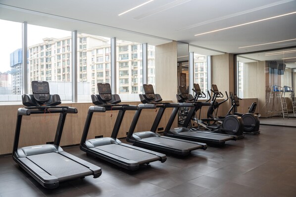 A gym with treadmills, elliptical machines, and stationary bikes arranged in rows. - Crowne Plaza Shangluo (Shanglou)
