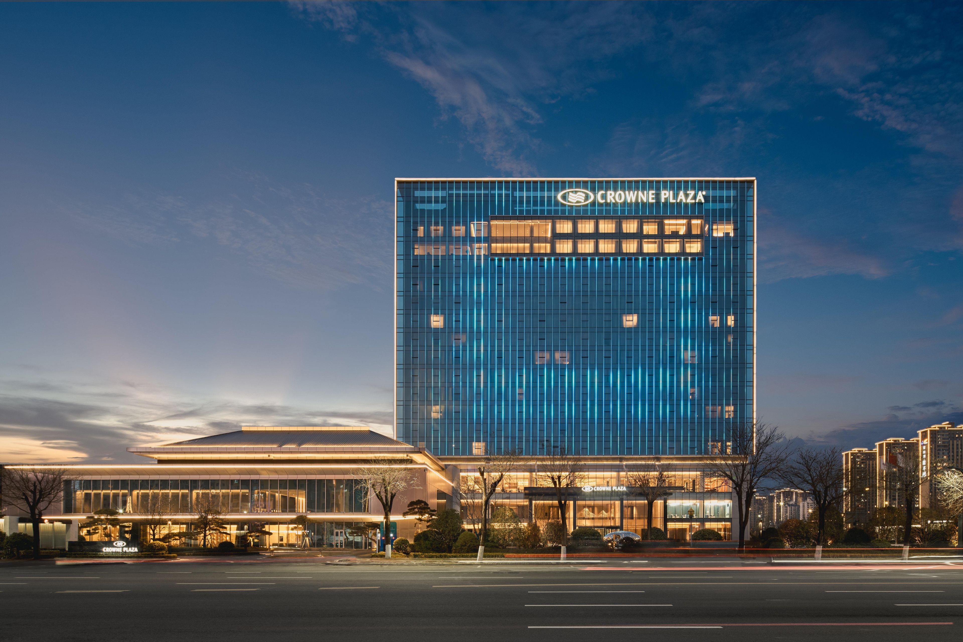 Un hotel moderno con una fachada de vidrio llamativa, una entrada bien iluminada y el nombre de la marca claramente visible.